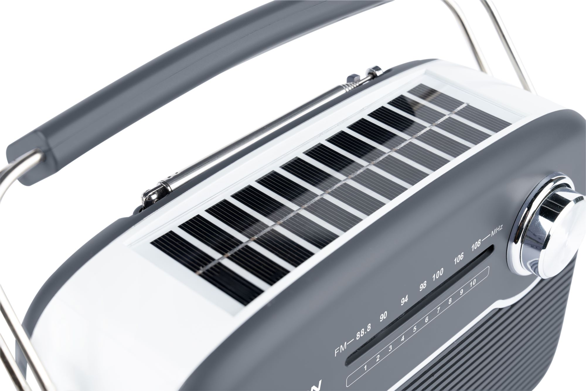 Szare i białe radio z panelami słonecznymi. Srebrny uchwyt i pokrętło. Numery wskazują częstotliwość i głośność.