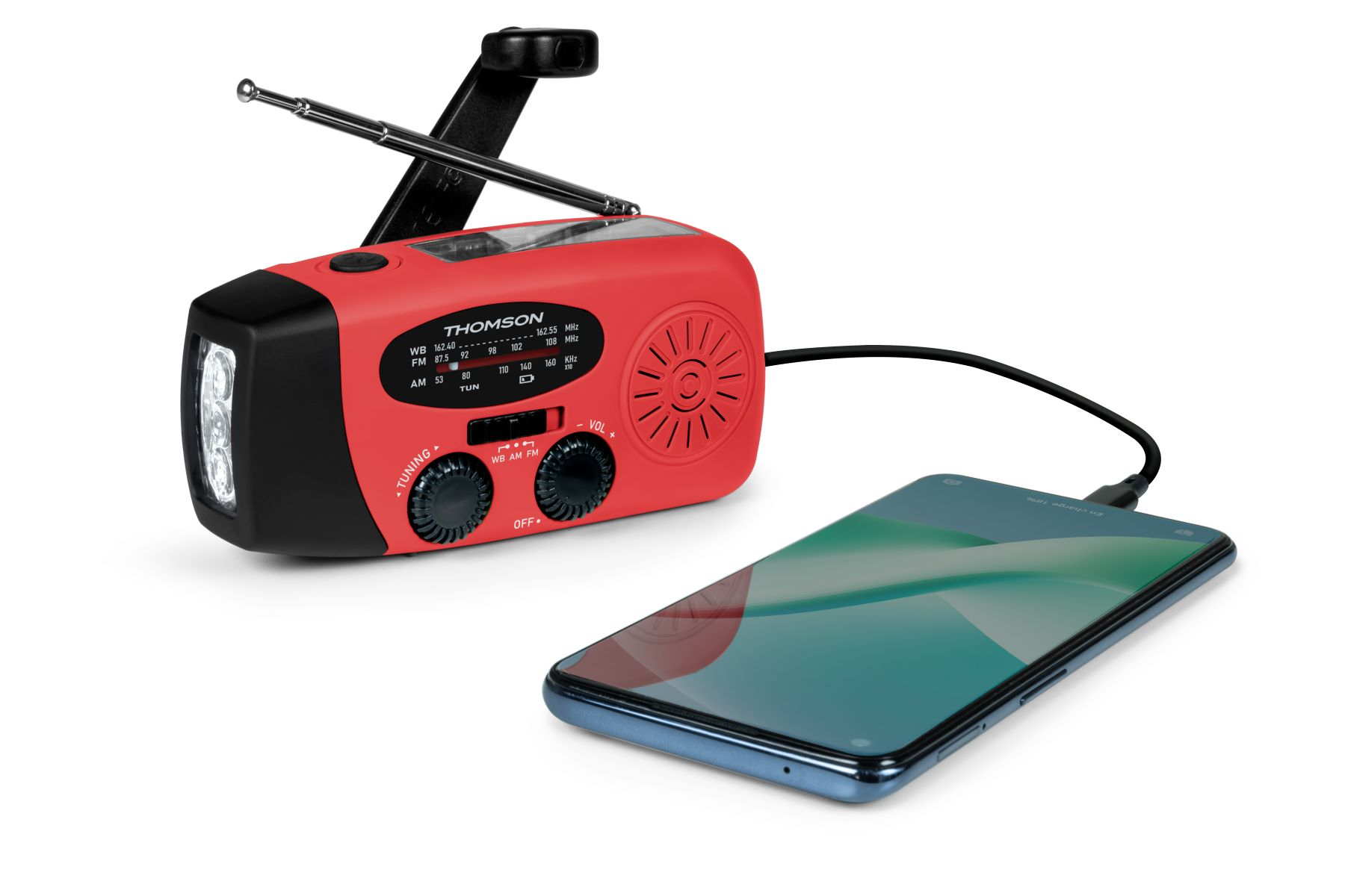Una radio Thomson roja y negra con linterna carga un smartphone mediante un cable negro.