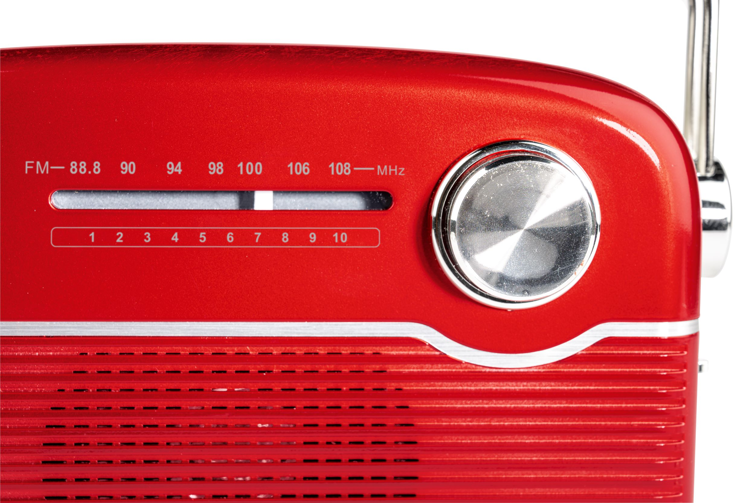 Zbliżenie czerwonego radia, pokazujące tarczę, numery i pokrętło strojenia.