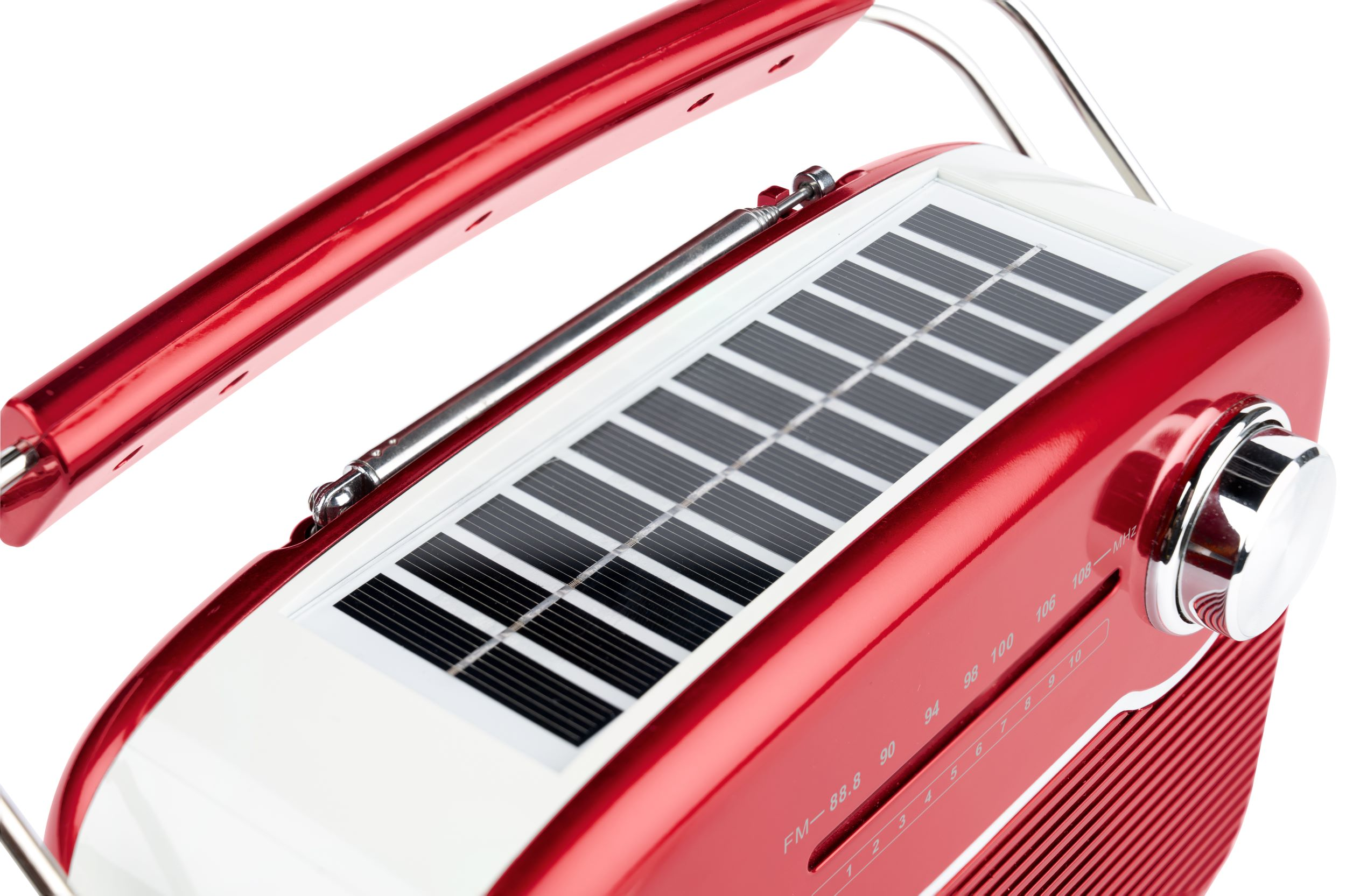Czerwone radio z panelem słonecznym na górze. Ma uchwyt i pokrętło strojenia. Białe tło.