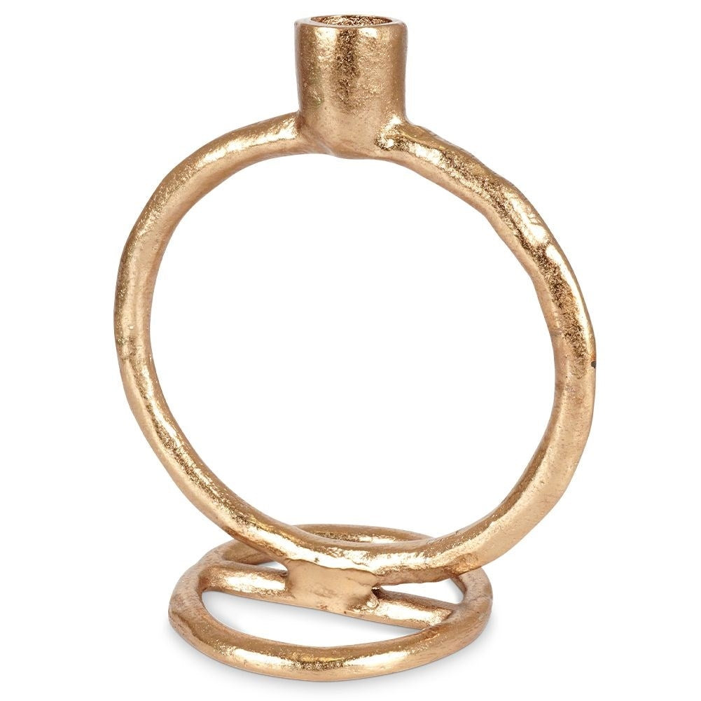 Un candelabro dorado en forma de anillo. Tiene una base circular, un anillo grande y un pequeño soporte cilíndrico.