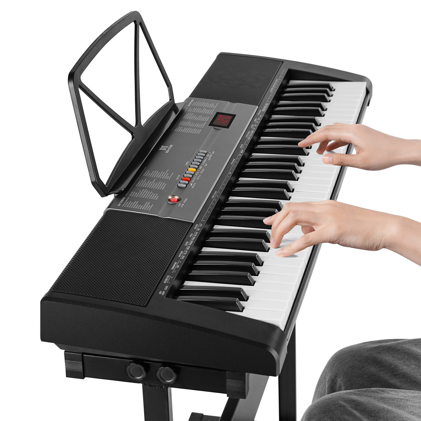 Eine Person spielt ein schwarz-weißes Keyboard. Das Keyboard steht auf einem Ständer, und es gibt einen Notenhalter.