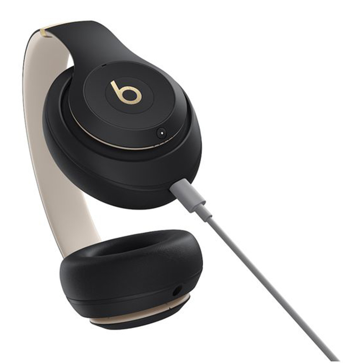 Schwarze Beats-Kopfhörer mit goldenen Akzenten und einem hellgrauen Kabel. Das Kopfband ist beige. Der Hintergrund ist weiß.