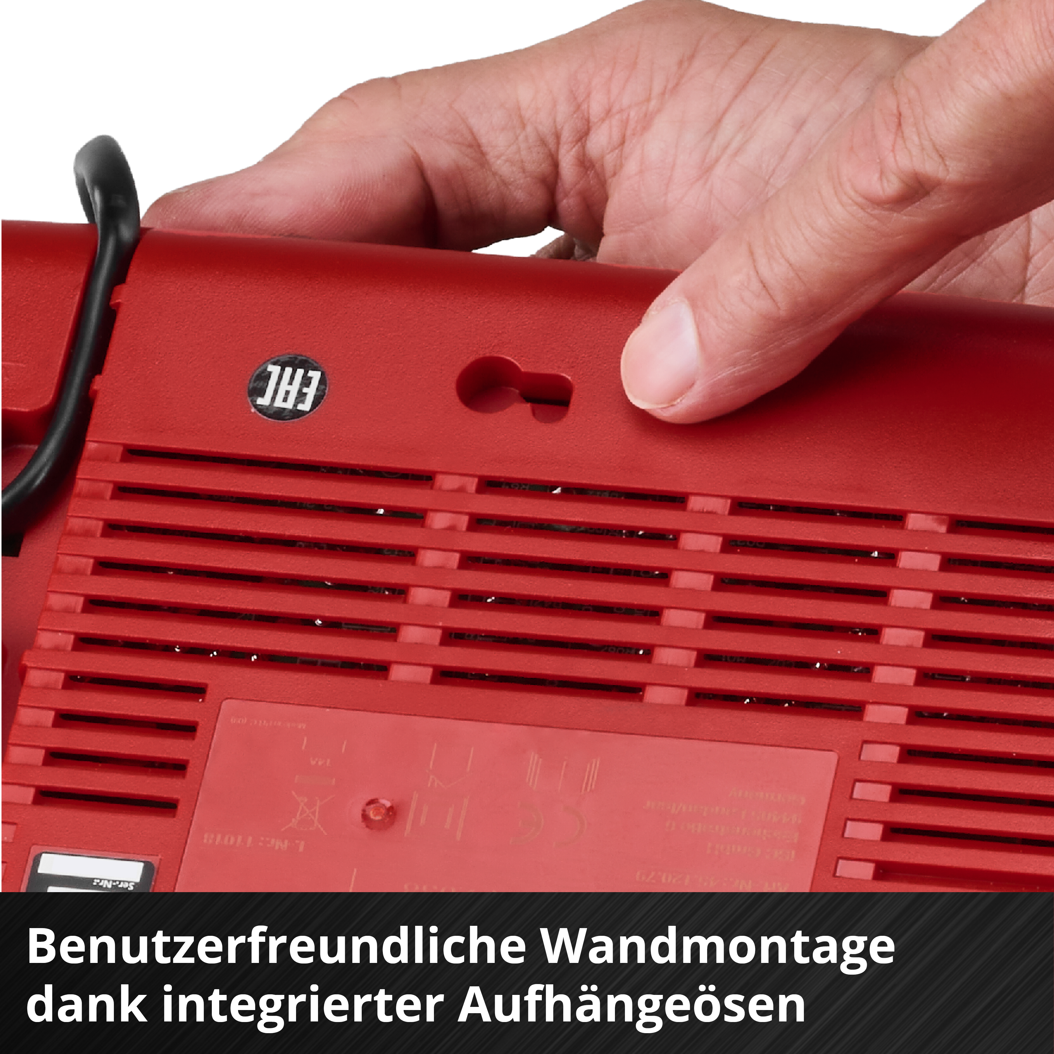 Rotes Gerät mit Hand, die es hält. Merkmale sind ein Aufhängeloch, Lüftungsschlitze und ein Aufkleber. Deutscher Text unten.