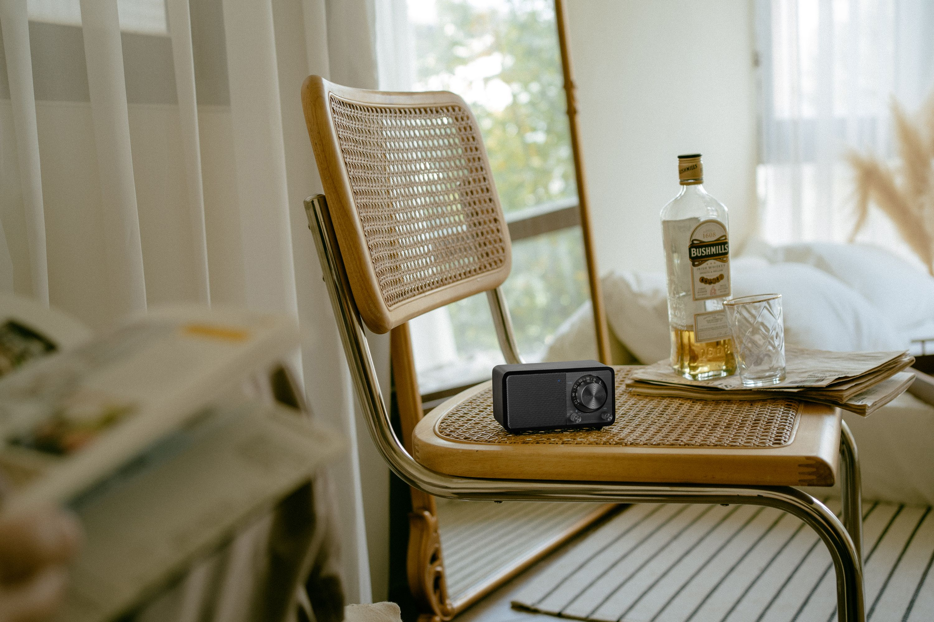 Ein Raum mit einem Radio auf einem Stuhl, Whiskey, Glas und Zeitung.