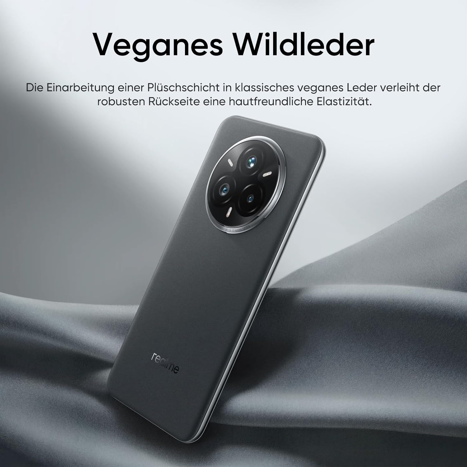 Un smartphone gris oscuro con varias cámaras traseras, sobre un fondo de tela gris. El texto dice 'Veganes Wildleder'.