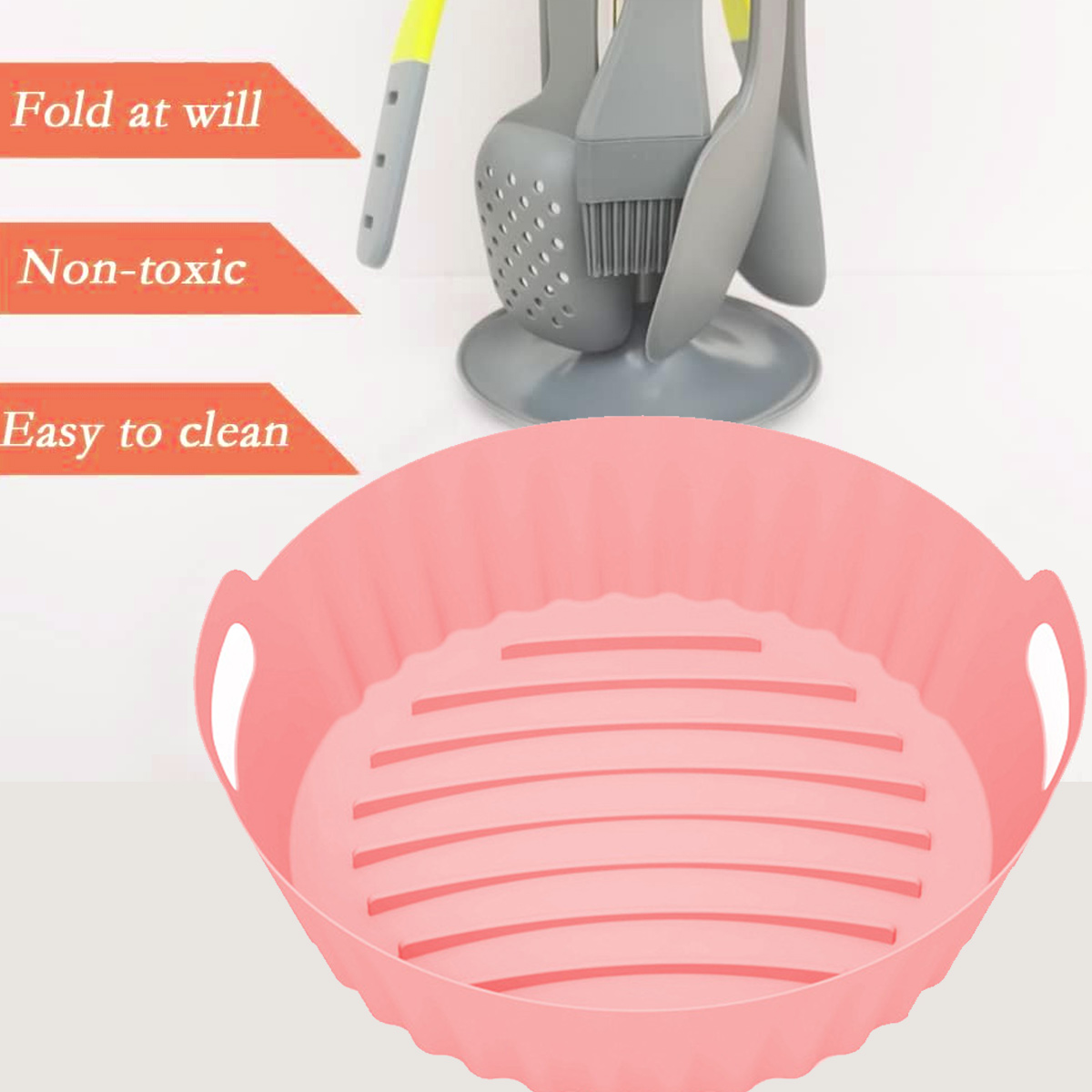 Ein pinkfarbener Silikon-Airfryer-Korb. Küchenutensilien stehen dahinter. Text: Nach Belieben falten, ungiftig, leicht zu reinigen.