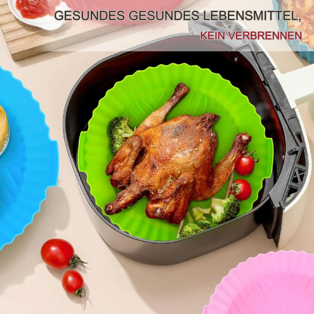 Gebratenes Hähnchen mit Brokkoli und Tomaten in einem Airfryer. Grüner Silikoneinsatz. Text oben auf Deutsch.