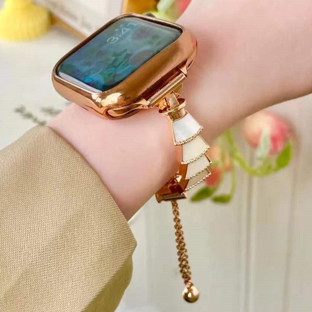 Eine goldene Uhr mit dekorativem Armband befindet sich an einem Handgelenk. Das Zifferblatt zeigt 3:41. Das Band hat weiße und goldene Details.
