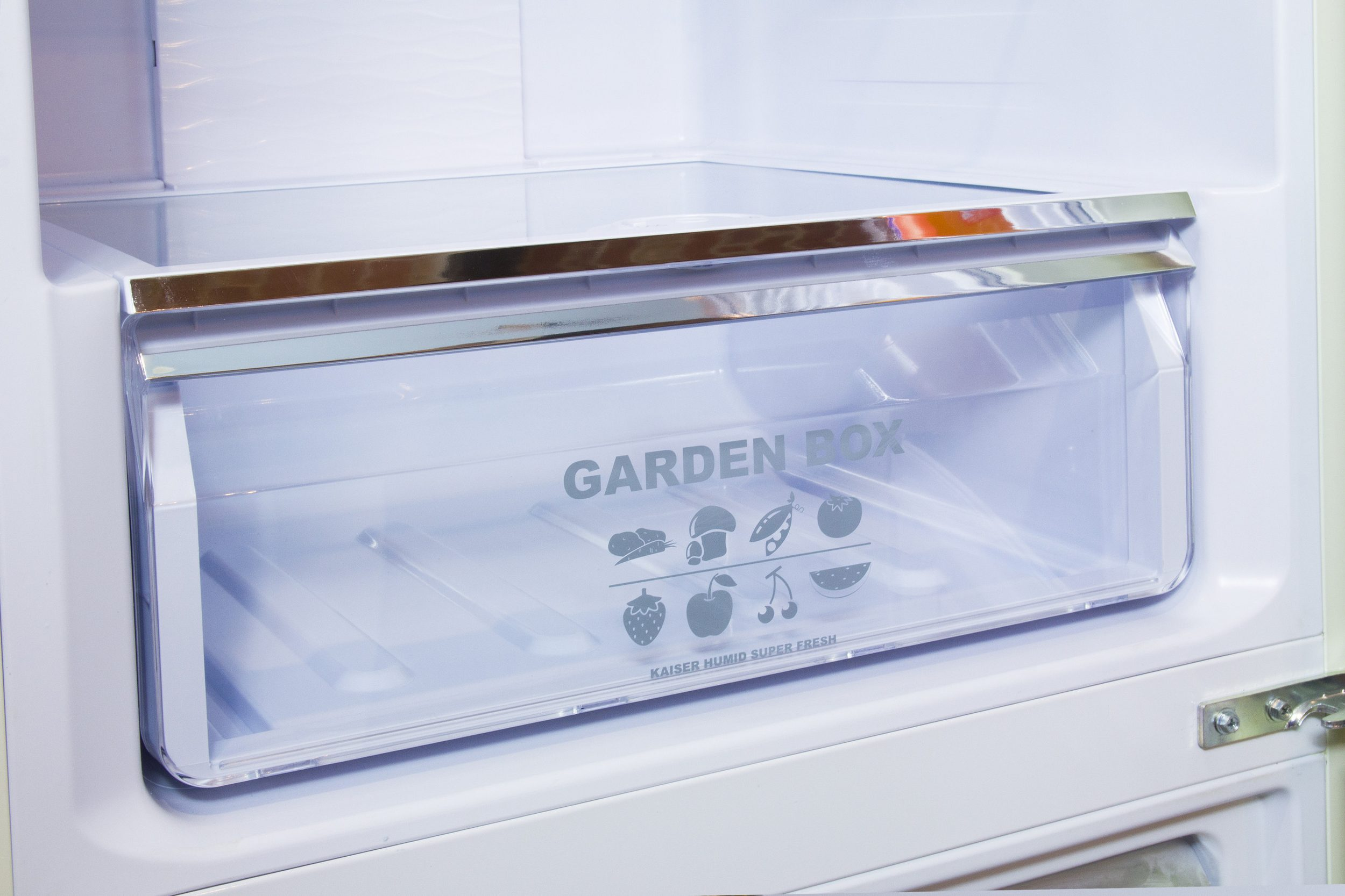 Im Kühlschrank ist eine transparente 'Garden Box' zu sehen. Sie enthält Icons von Obst und Gemüse.