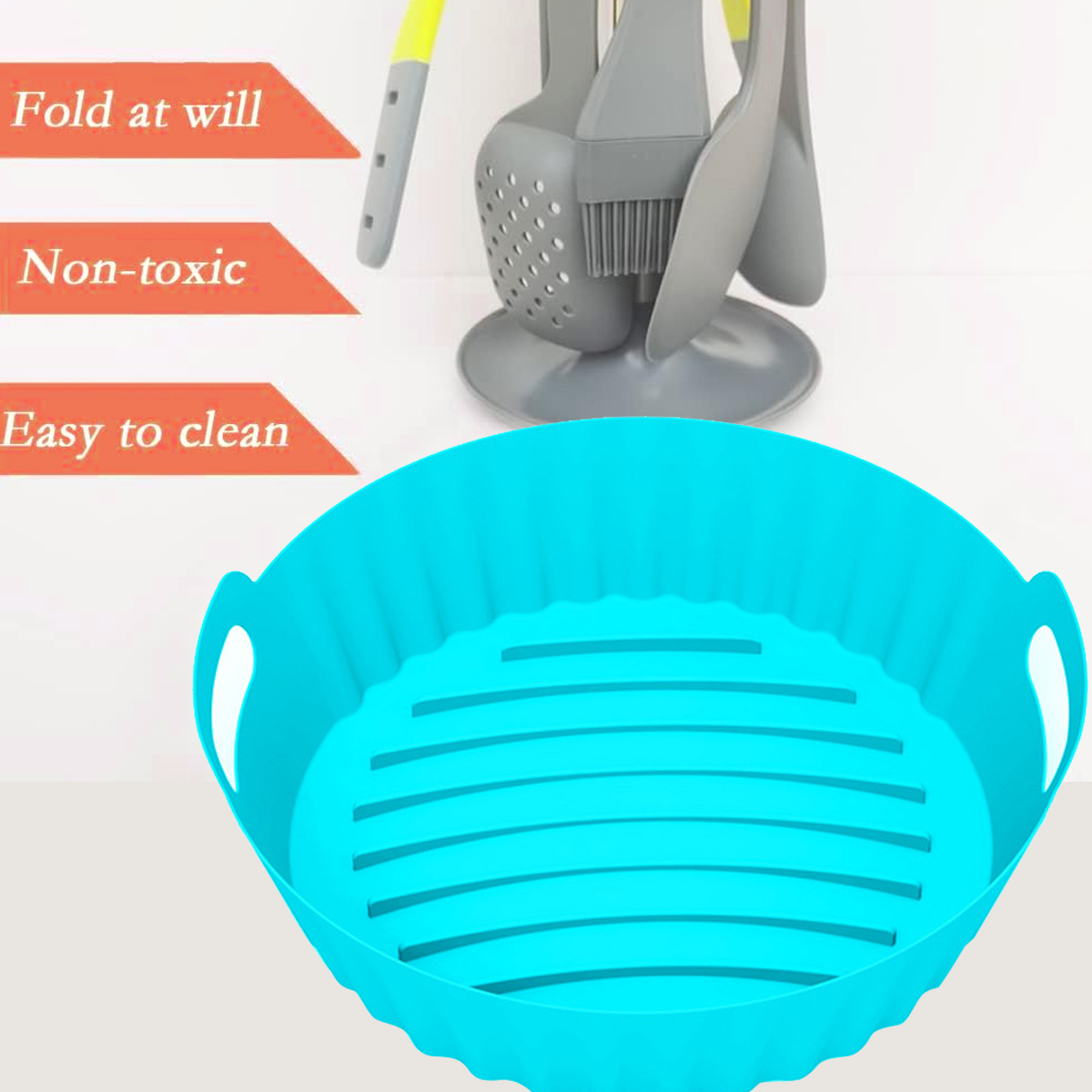 Ein blauer Silikon-Airfryer-Korb steht im Mittelpunkt. Graue Kochutensilien sind im Hintergrund. Der Text lautet 'Fold at will', 'Non-toxic', 'Easy to clean'.