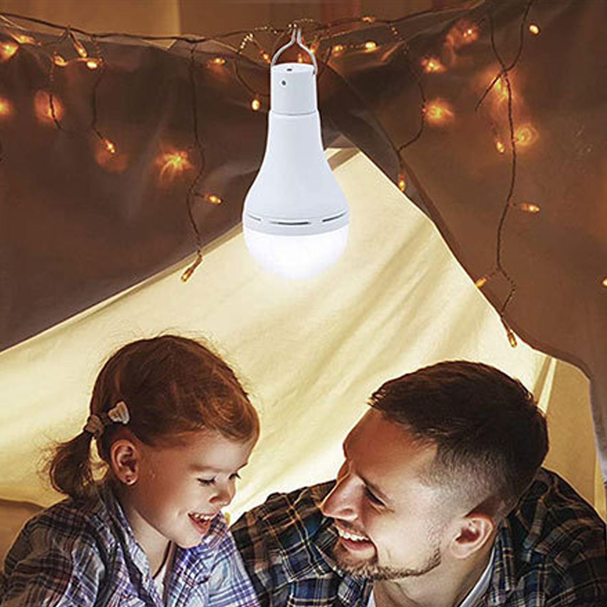 Ein Mann und ein Mädchen lächeln unter einem Zelt, das von einer hängenden weißen Lampe beleuchtet wird. Lichterketten schmücken die Zeltdecke.