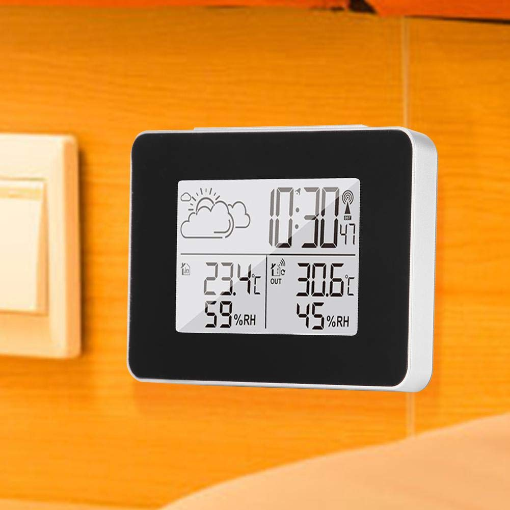 Eine Digitaluhr zeigt 10:30 Uhr, Temperatur und Luftfeuchtigkeit an. Sie befindet sich an einer gelben Wand mit Lichtschalter.