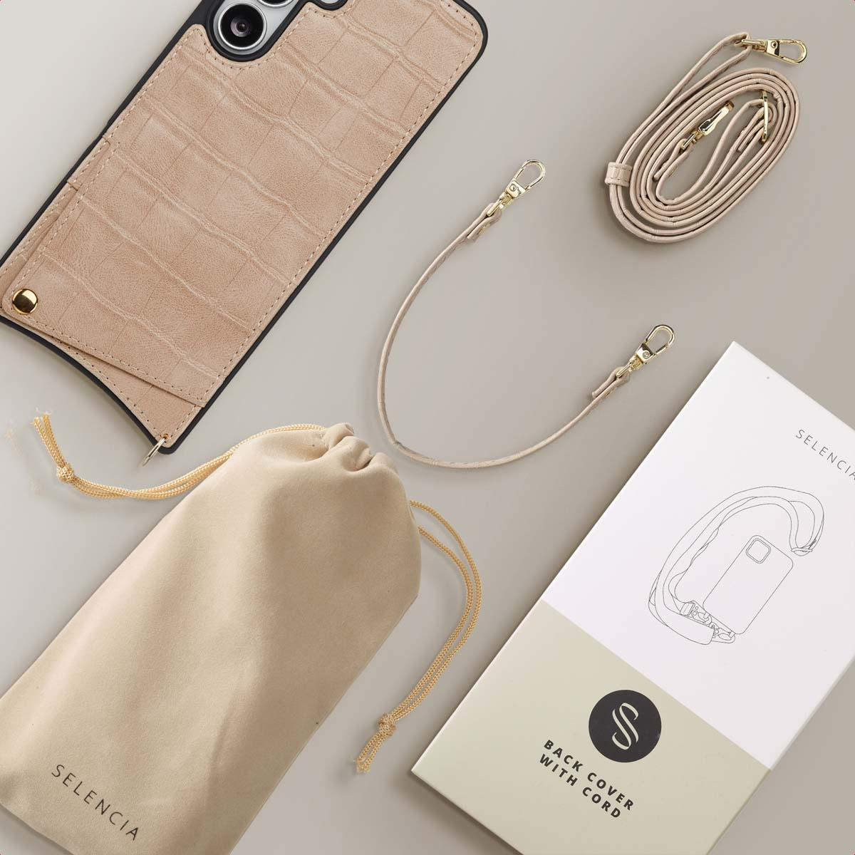 Beige telefoonhoesje met krokodillenpatroon, beige zakje, telefoonriem en doos met tekst 'Back Cover with Cord'.