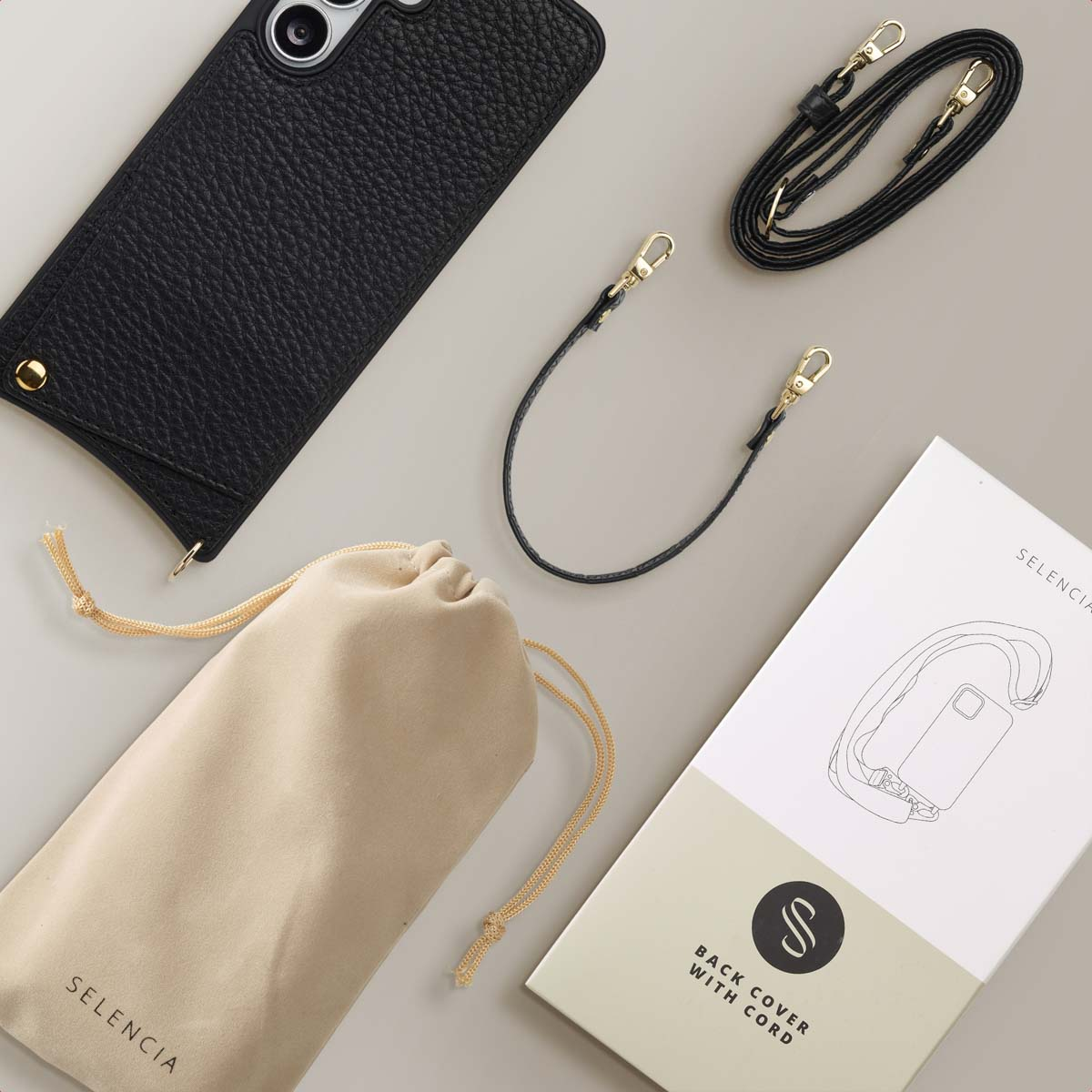 Zwarte telefoonhoes, riem en etui op een grijze ondergrond. Inclusief verpakking met telefoonillustratie.