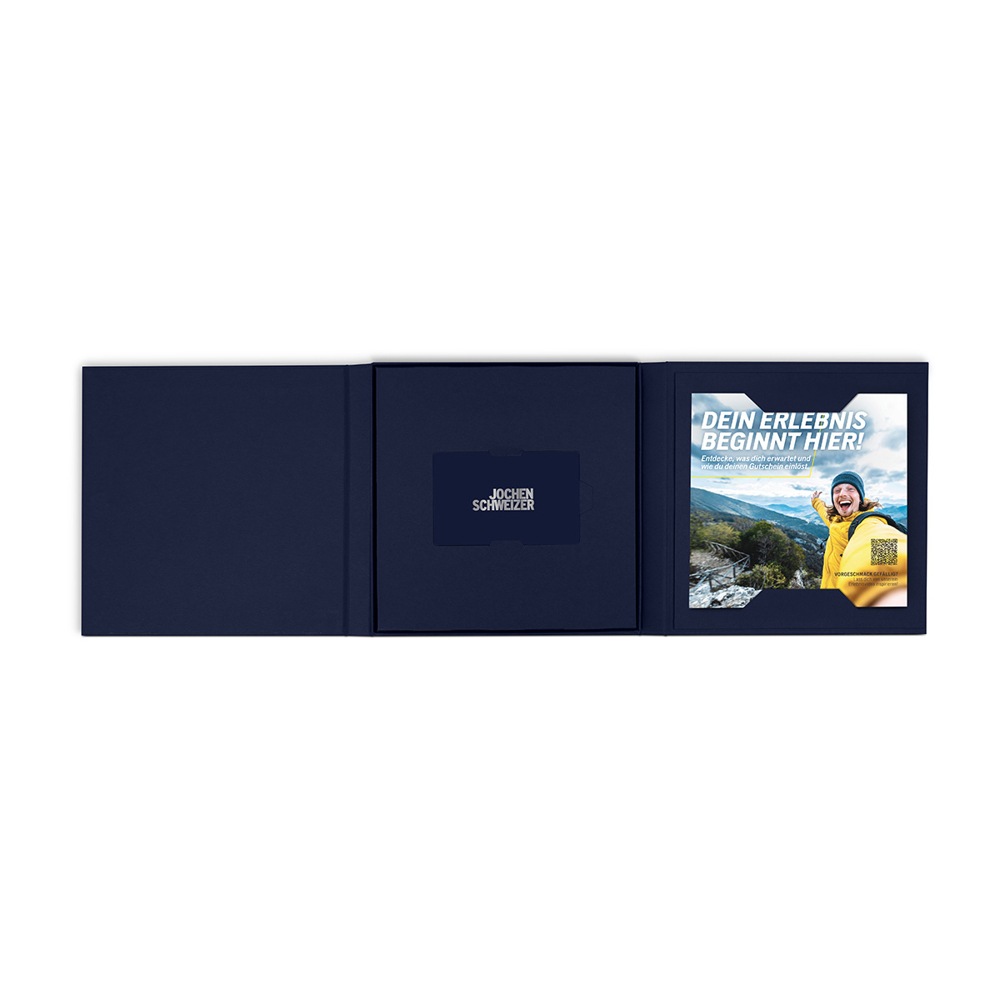 Eine dunkelblaue Box ist geöffnet und zeigt eine Karte und einen Flyer mit dem Text "DEIN ERLEBNIS BEGINNT HIER!" und einem Mann.