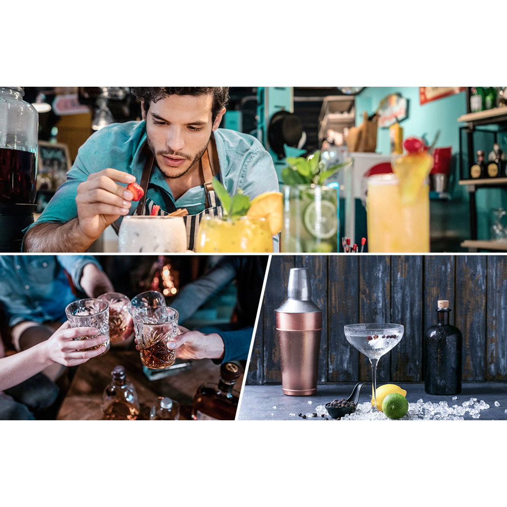 Ein Barkeeper gibt eine Erdbeere in einen Cocktail. Leute stoßen mit Whiskeygläsern an. Shaker, Cocktail und Flasche auf einem Tisch.
