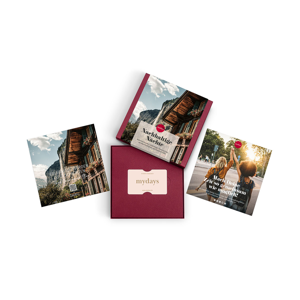 Vier mydays-Werbeartikel. Eine Box, drei Broschüren, alle mit dem mydays-Logo. Bilder von Natur, Menschen und Gebäuden sind sichtbar.