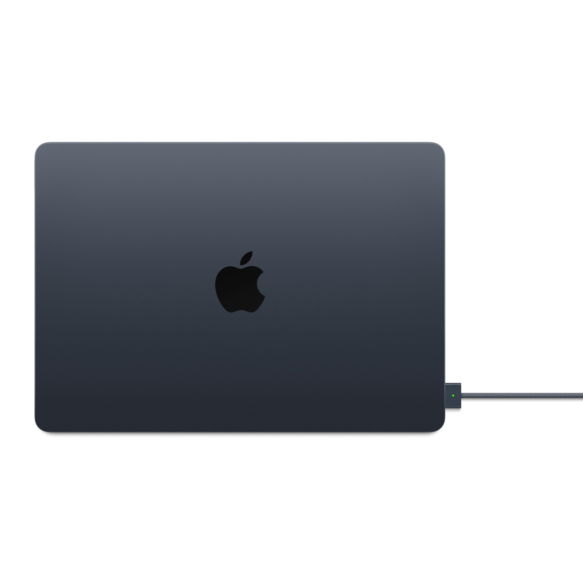 Un ordinateur portable gris foncé avec un logo Apple, connecté à un câble d'alimentation sur fond blanc.