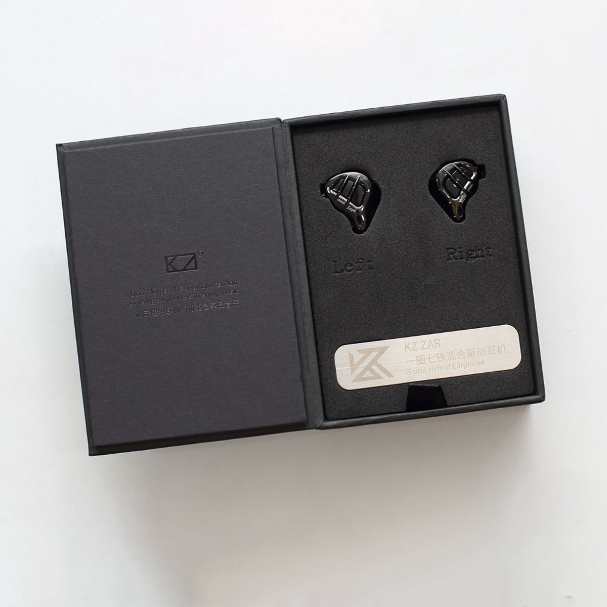 Open zwarte doos met oortelefoons met de labels 'Links' en 'Rechts'. Een zilveren plaat leest 'KZ ZAR 8-unit Hybrid Earphone'.
