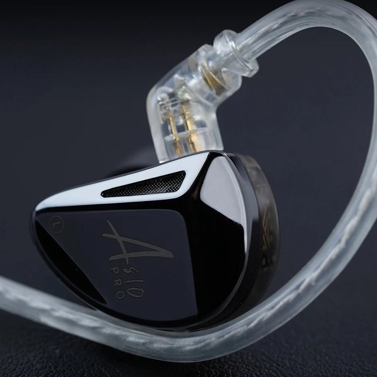 Close-up of a black and white in-ear monitor. Transparent cable and ear fitting. The text "A310 PRO" is visible.