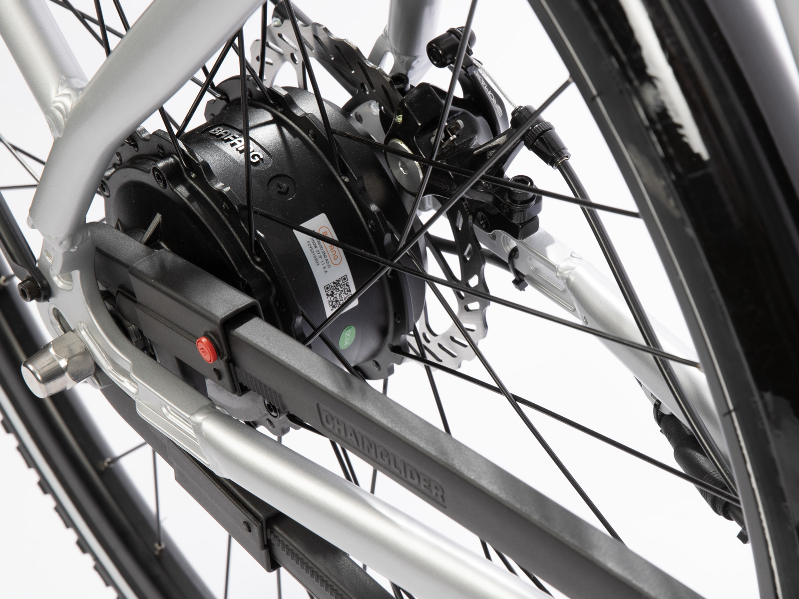 Close-up van een fietswiel met een zwarte motor, zilveren frame, kettingbeschermer en remonderdelen. De spaken zijn zichtbaar.