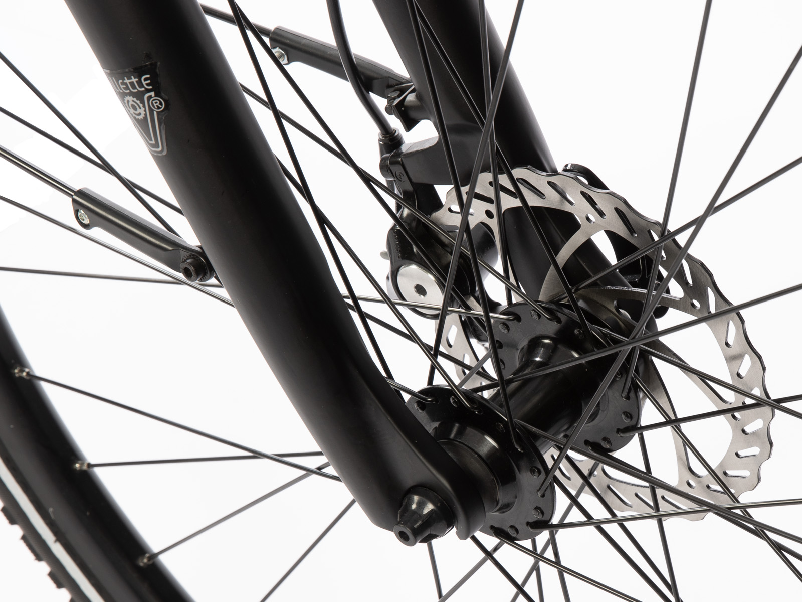 Close-up van een zwart fietswiel met spaken, een schijfrem en de voorvork. De achtergrond is wit.