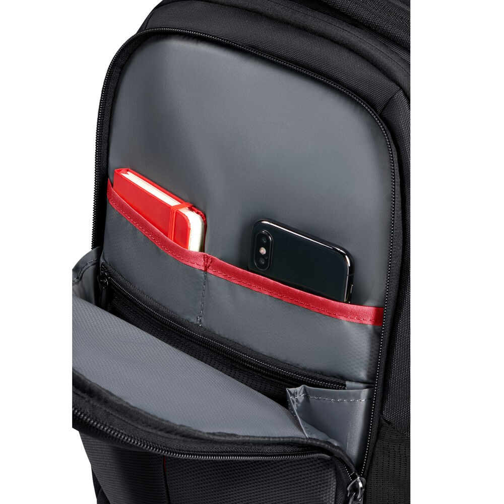 Schwarzer Rucksack mit offener Tasche. Innen sind ein rotes Notizbuch und ein schwarzes Smartphone zu sehen. Graues Futter, roter Rand und Reißverschluss.