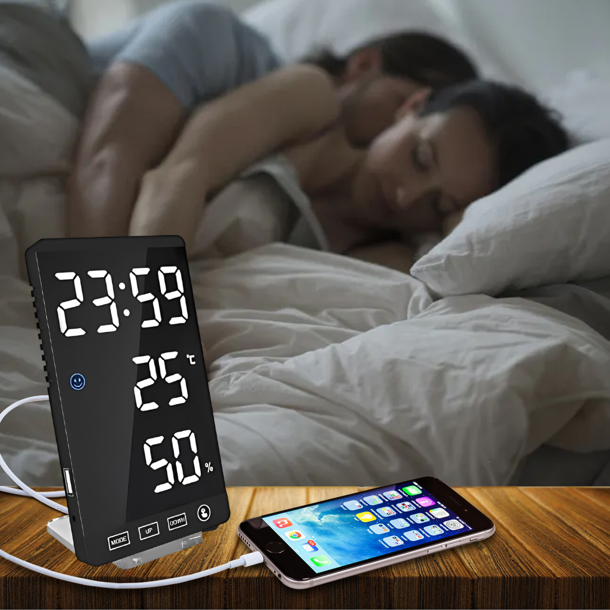 Paar im Bett mit Digitaluhr, die Zeit, Temperatur und Luftfeuchtigkeit anzeigt. Ein Telefon wird auf dem Tisch aufgeladen.