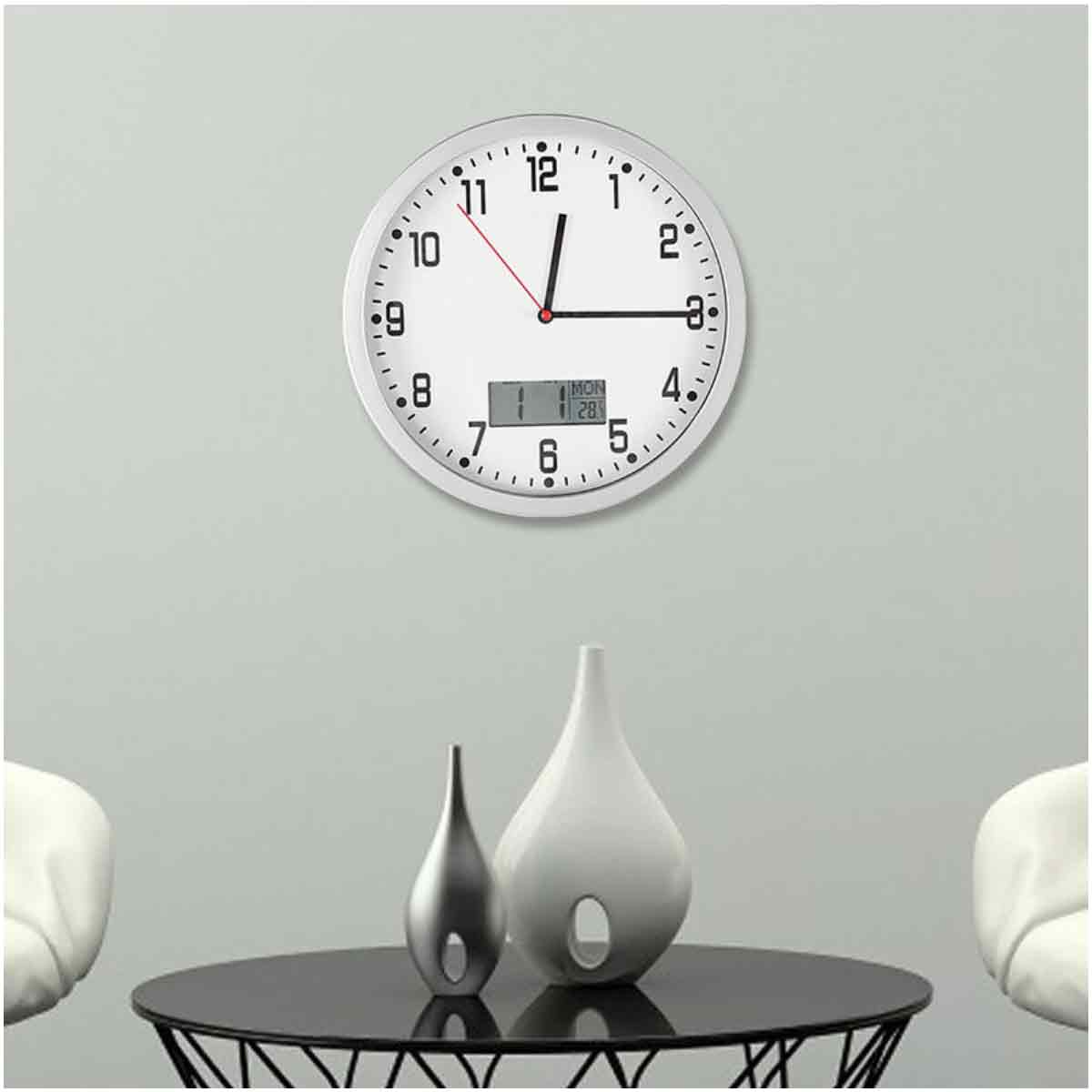 Eine weiße Uhr an einer grauen Wand. Darunter ein schwarzer Tisch mit zwei Vasen. Eine ist silber, die andere weiß.