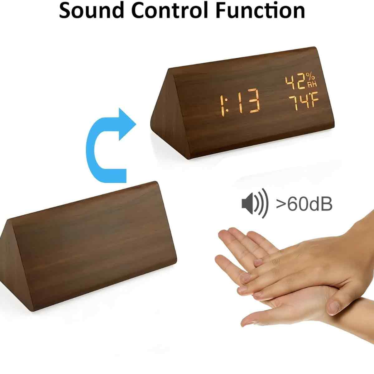 Ein hölzerner Wecker zeigt Zeit, Luftfeuchtigkeit und Temperatur an. Eine Hand klatscht in der Nähe, was die Tonsteuerungsfunktion anzeigt.