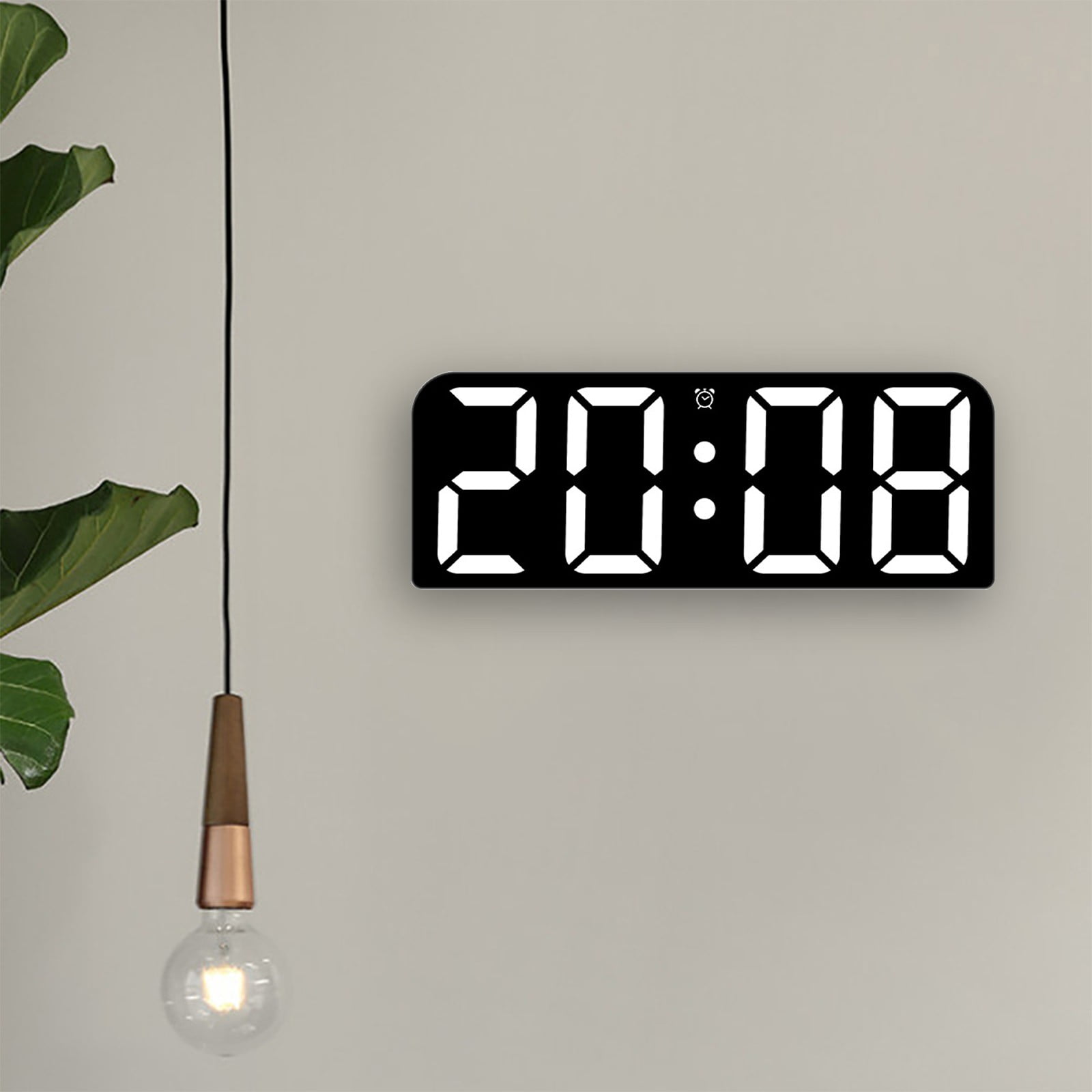 Eine Digitaluhr zeigt 20:08 an einer beigen Wand. Eine Hängeleuchte und eine grüne Pflanze sind im Bild.