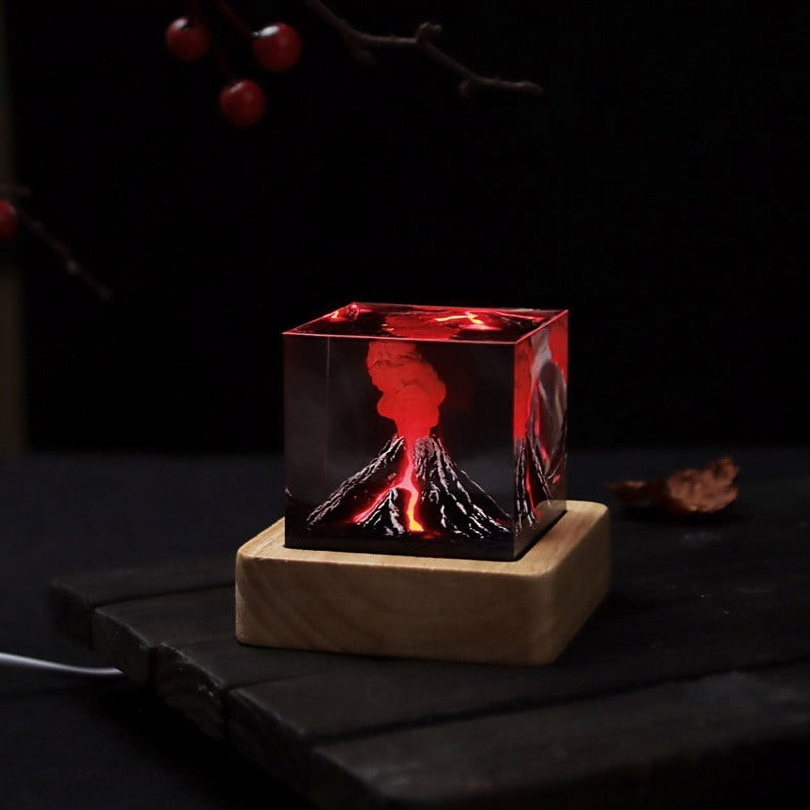 Ein leuchtendes Vulkanmodell in einem Würfel. Rote Lava bricht aus dem Vulkan aus. Dunkler Hintergrund mit roten Beeren und einem Holzsockel.