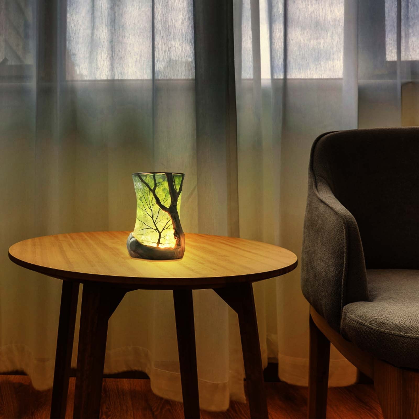 Eine beleuchtete Baumskulptur aus Glas steht auf einem Holztisch. Ein grauer Stuhl steht neben dem Tisch. Dahinter sind transparente Vorhänge.