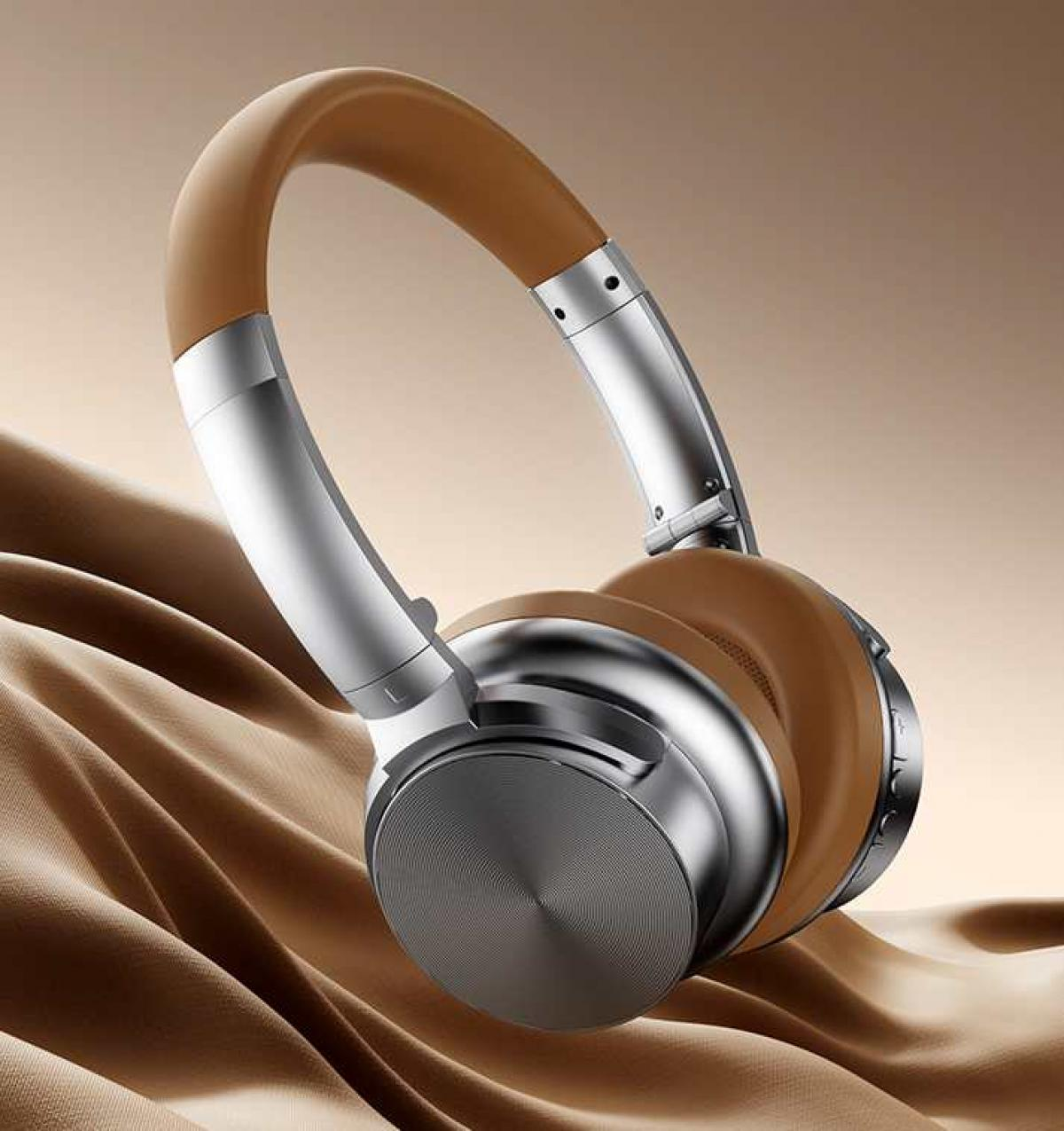 Over-Ear-Kopfhörer mit braunen Ohrmuscheln und Kopfbügel, silbernen Akzenten, die auf drapiertem Stoff liegen. Der Hintergrund ist ein Tan-Farbverlauf.