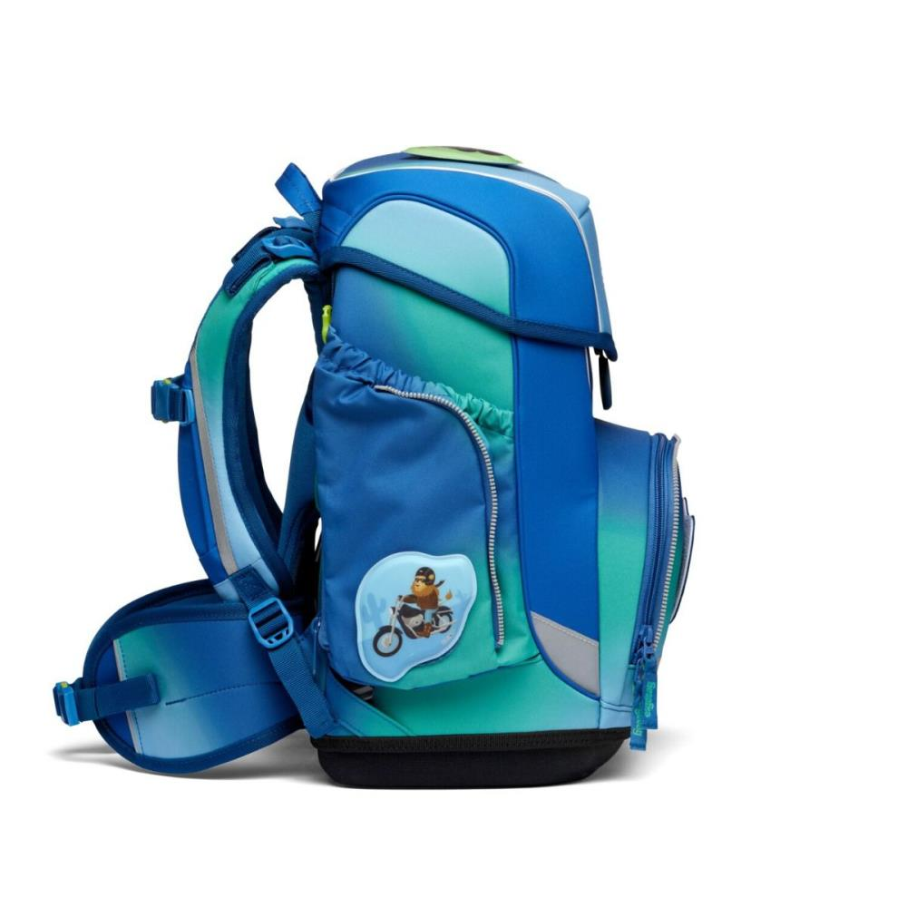 Ein blau-grüner Rucksack mit einem Cartoon-Aufkleber eines Bären auf einem Motorrad. Er hat mehrere Fächer und einen Reißverschluss.