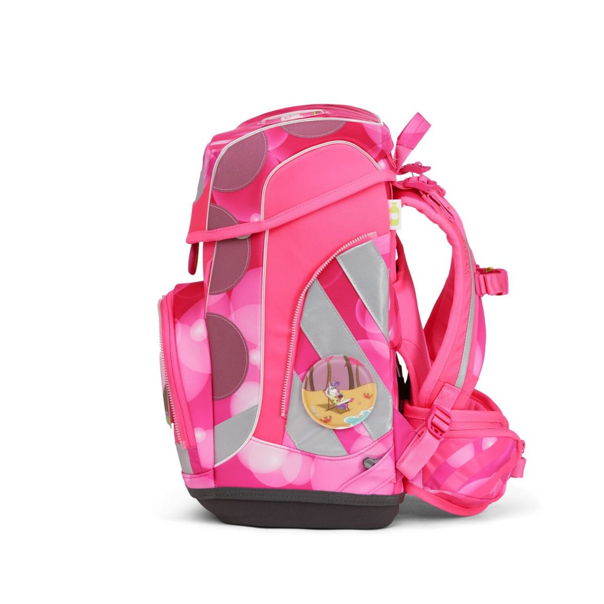 Pinkfarbener Schulrucksack mit Kreisen, einem Cartoon-Abzeichen und reflektierenden Streifen. Er hat einen dunkelgrauen Boden und rosa Träger.