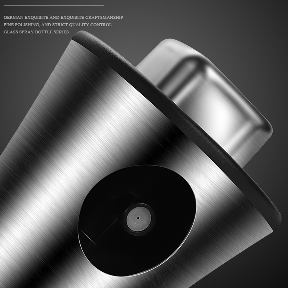 Nahaufnahme einer Glassprühflasche. Sie hat einen metallischen Körper mit schwarzer Düse und glänzendem Deckel. Der Hintergrund ist dunkelgrau.