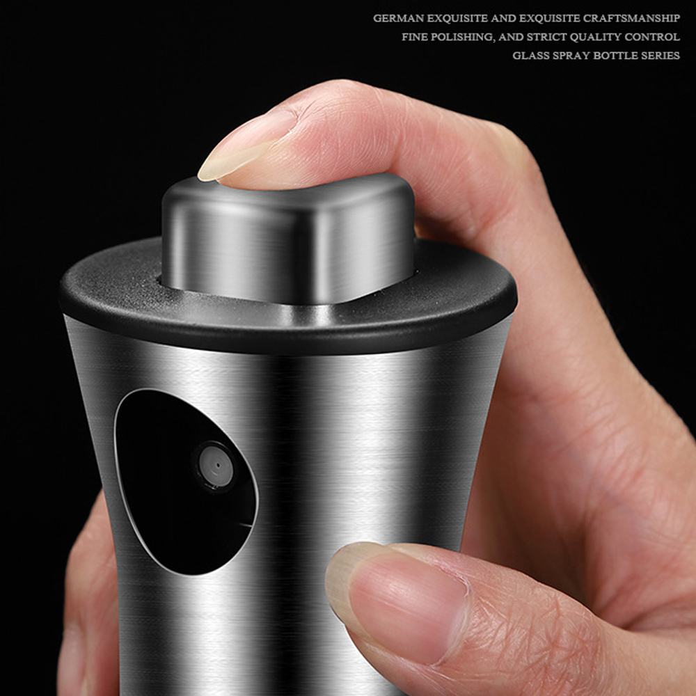 Eine Hand drückt auf die Düse einer silbernen Sprühflasche. Die Flasche ist aus Edelstahl, der Hintergrund ist schwarz.