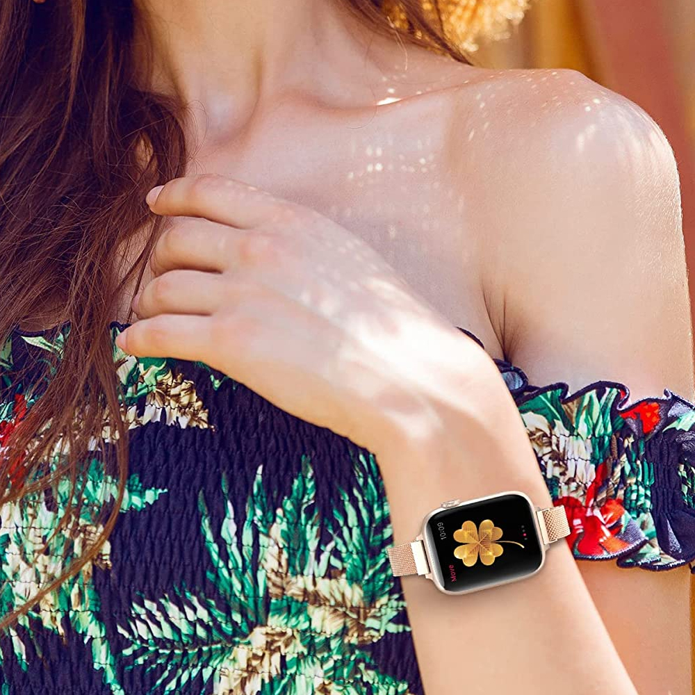 Eine Frau trägt ein Oberteil mit Blumenmuster und eine goldene Uhr mit einem Kleeblatt auf dem Bildschirm. Ihr Arm ist erhoben.