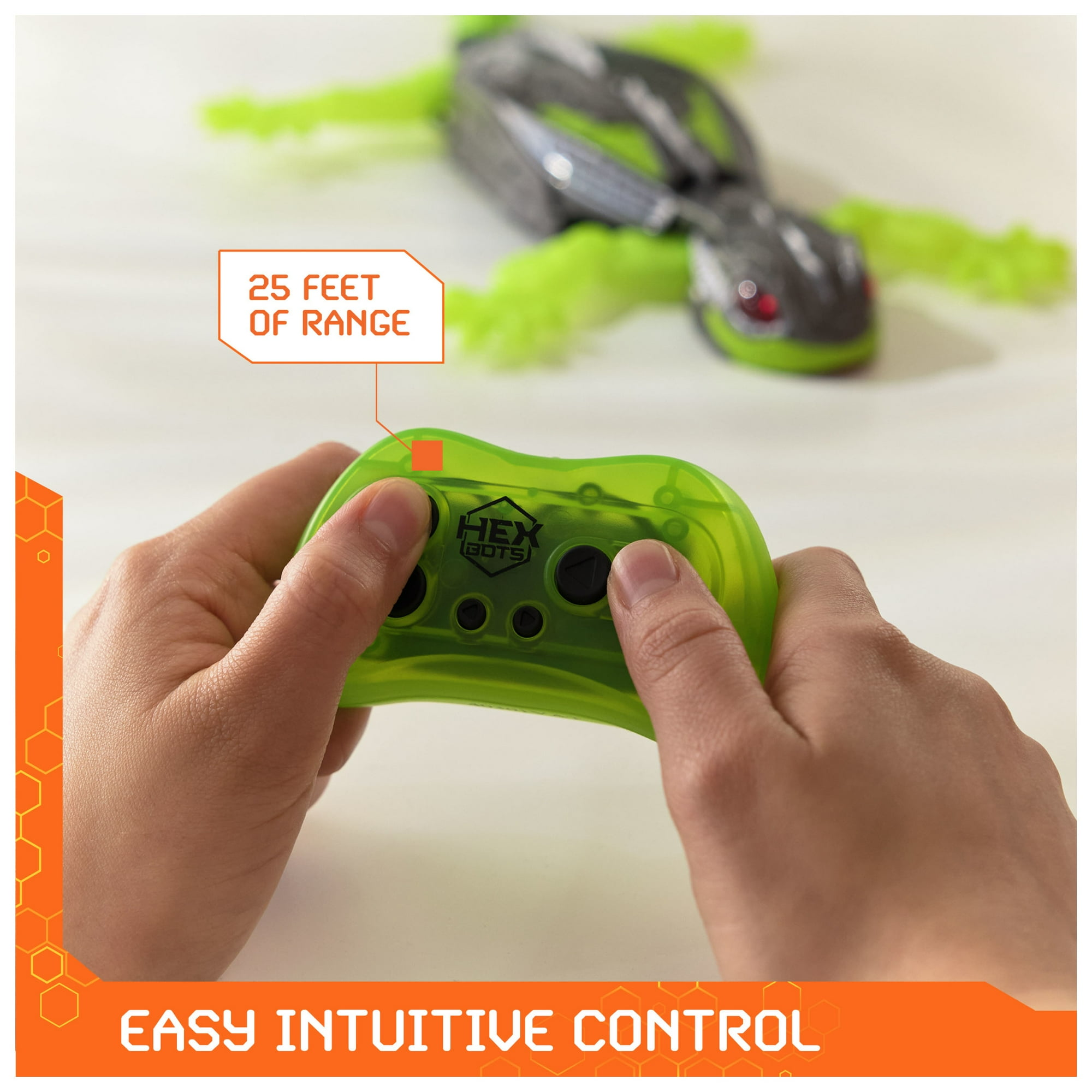 Hände halten einen grünen Controller. Ein Spielzeug-Eidechse im Hintergrund, beschriftet mit '25 FEET OF RANGE' und 'EASY INTUITIVE CONTROL'.
