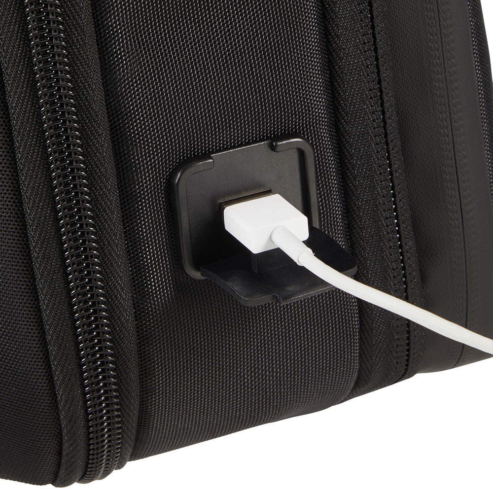 Primo piano di una borsa nera con un cavo USB bianco collegato a una porta nera. La borsa ha una cerniera e una superficie strutturata.