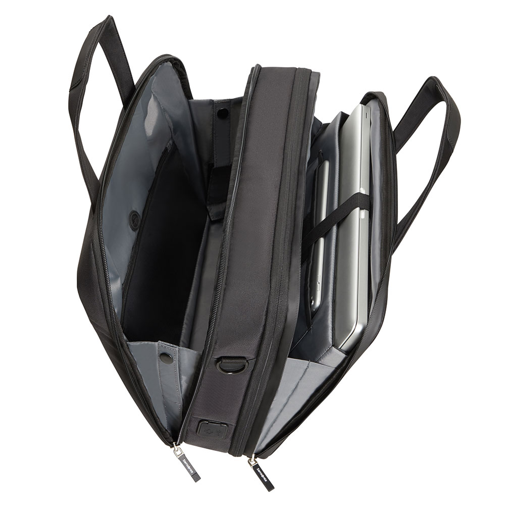 Valigetta nera aperta. Contiene laptop, tablet e vari scomparti. Cerniere e manici visibili. Interno grigio.