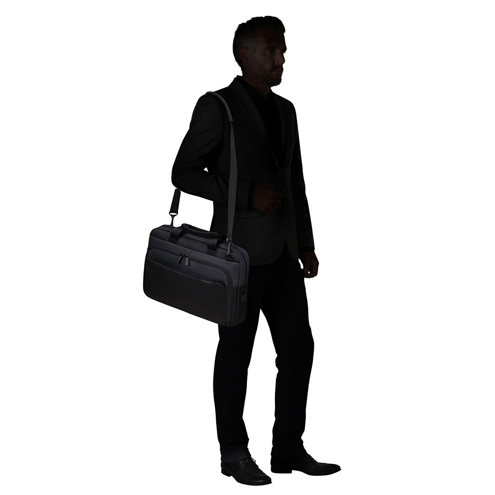 Un uomo in giacca e cravatta porta una valigetta nera sulla spalla. È in silhouette su sfondo bianco.