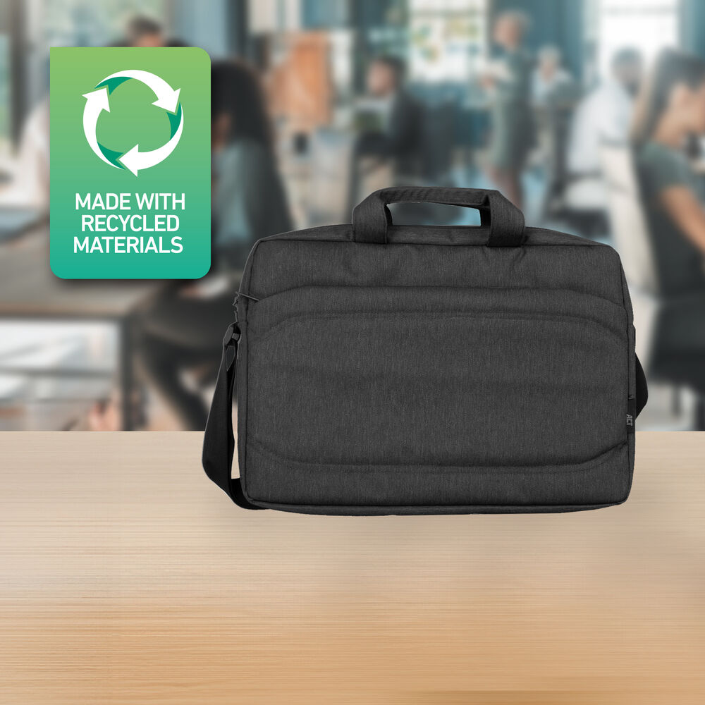 Eine dunkelgraue Laptoptasche liegt auf einem Holztisch. Ein Schild mit Recycling-Symbol sagt 'Hergestellt aus recycelten Materialien'. Verschwommener Bürohintergrund.