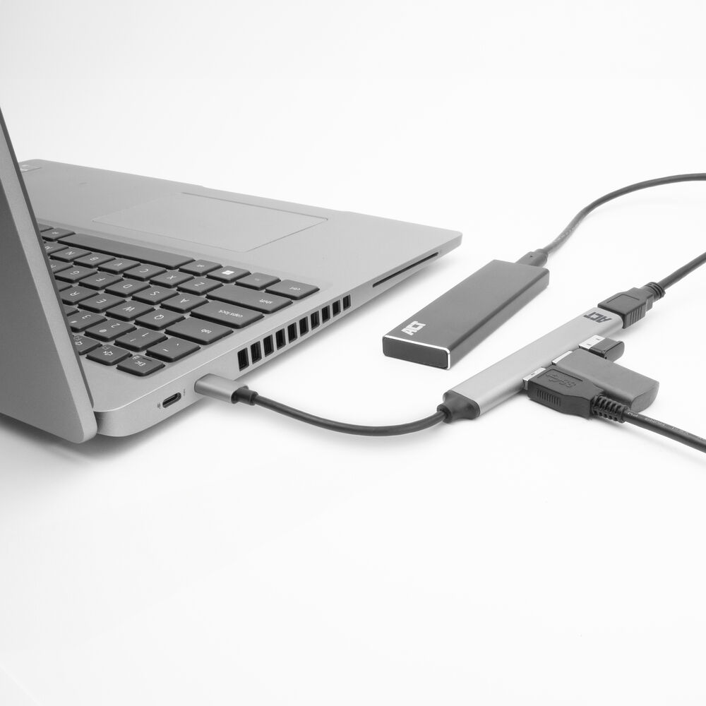 Laptop collegato a un hub e a un disco rigido esterno. L'installazione è su una superficie bianca.