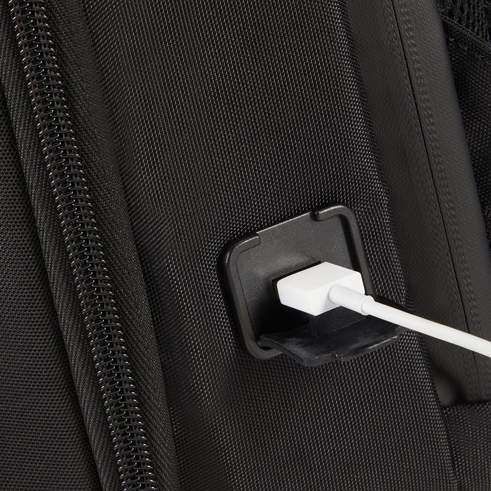 Nahaufnahme eines schwarzen Rucksacks mit einem weißen Ladekabel, das in einen Anschluss eingesteckt ist.