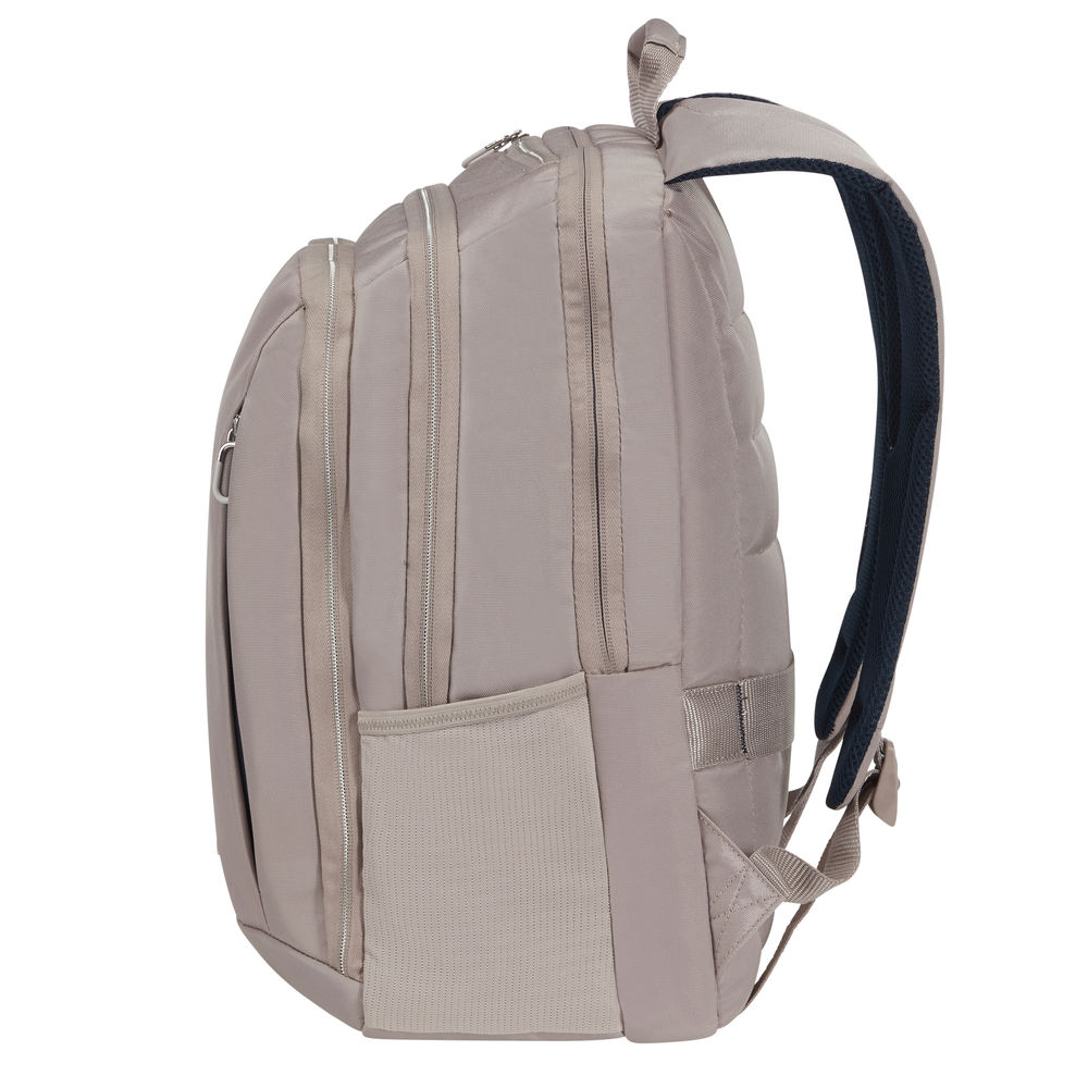 Uno zaino beige con scomparti e cerniere. Visibile un cinturino imbottito blu scuro. Su sfondo bianco.