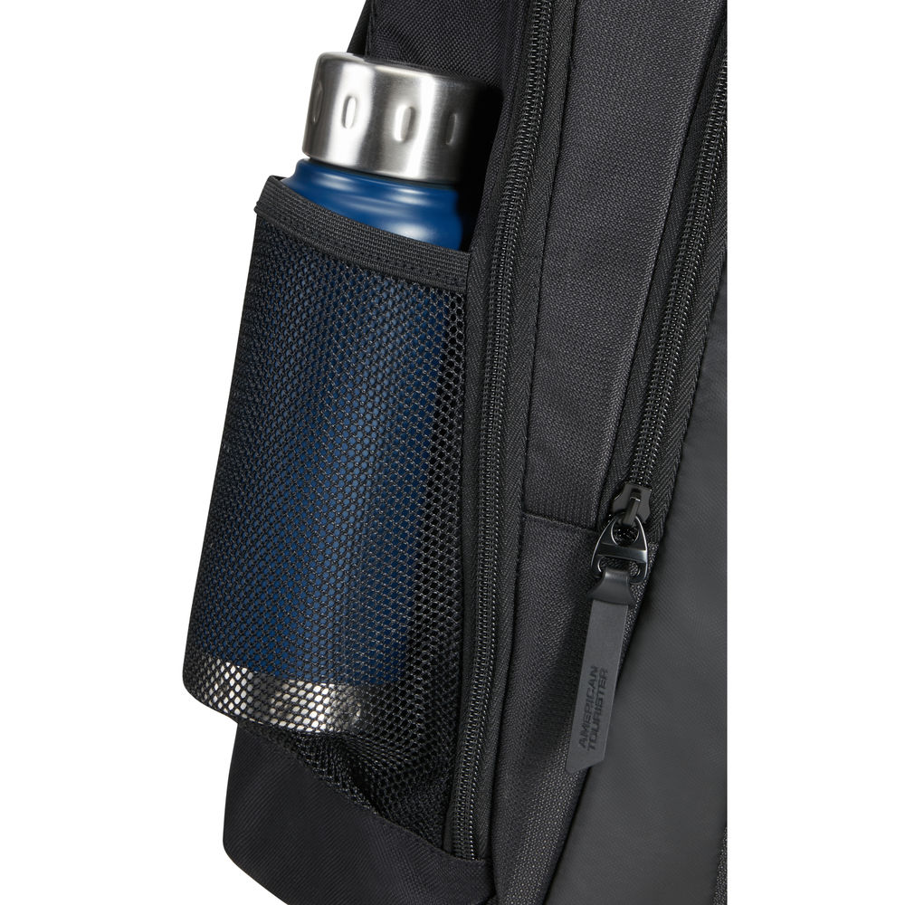 Nahaufnahme eines schwarzen Rucksacks mit einer Netztasche an der Seite. Eine blaue Wasserflasche befindet sich in der Tasche. Ein Reißverschluss ist sichtbar.