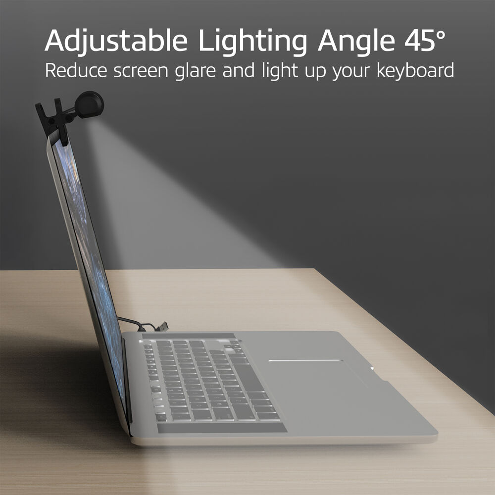 A laptop with a small light attached to the screen. The light shines on the keyboard. A wooden desk and grey background.